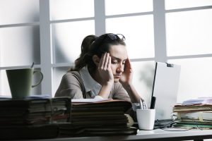 Exhasuted woman with headache at computer