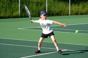 Boy playing tennis about to hit ball