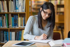 Woman writing in notepad in library