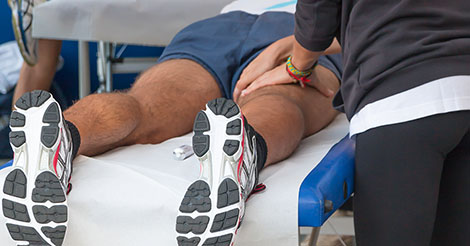 Athletic trainer working on athlete's hamstring injury