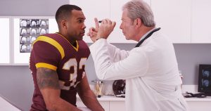 Doctor checking a football player for a sport-related concussion