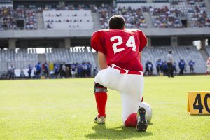 Football player kneels after an injury on a kickoff